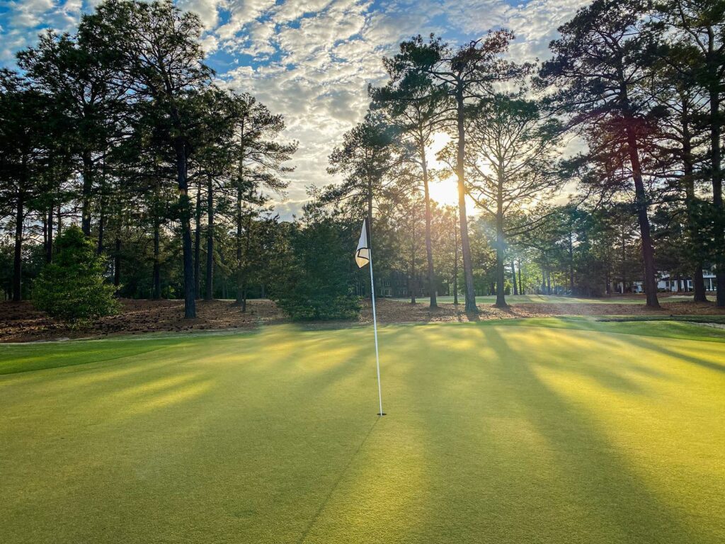 Columbia Country Club hole with flag surrounded by trees and partly cloudy sky