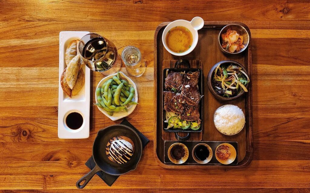Overhead view of trays with a spread of Korean food, soup, and sides