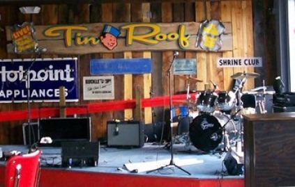 Instruments for a band to perform infront of a large "tin roof" sign on stage