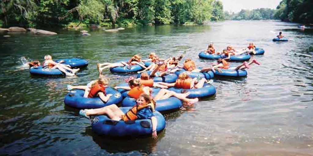 Group of 17 People in Blue Inner-tubes Floating Down a River