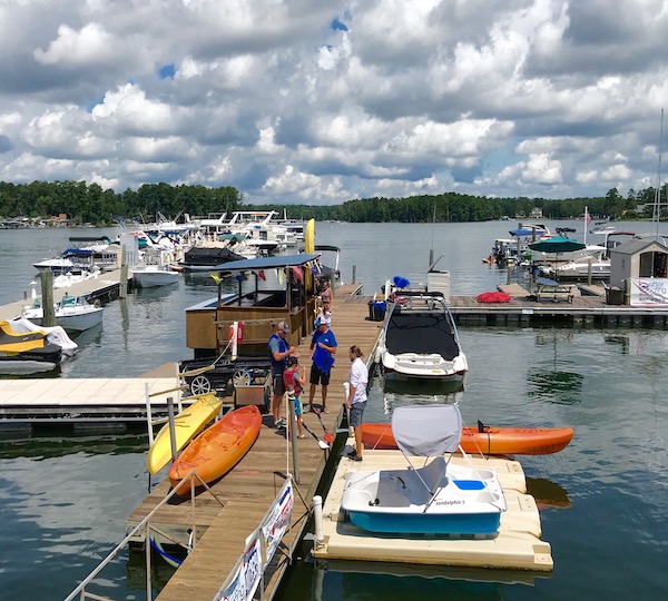 Several individuals standing on a marina dock surrounded by numerous boats.