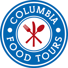 Blue circle with white inner circle, Text reads Columbia Food Tours