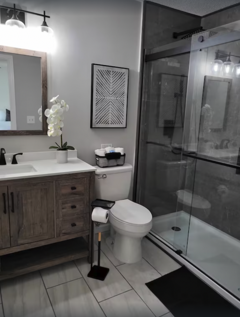 bathroom with sink, mirror, toilet, and glassed in shower