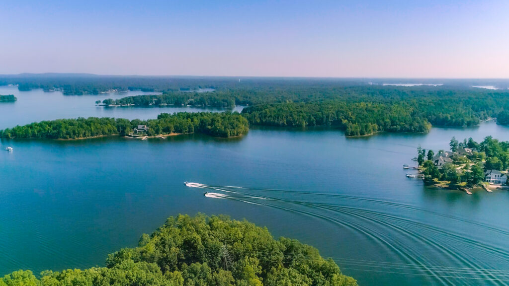 Two boats cruising across Lake Murray surrounded by lush greenery and blue water