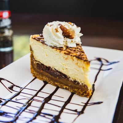 A delicious multi-layered cheese cake with whipped cream and chocolate syrup.