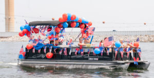 Pontoon boat with red, and blue balloons on the canopy, American flags decorate the boat