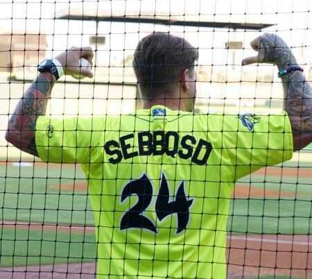 Man wearing neon green baseball jersey that says SEBBQSD24