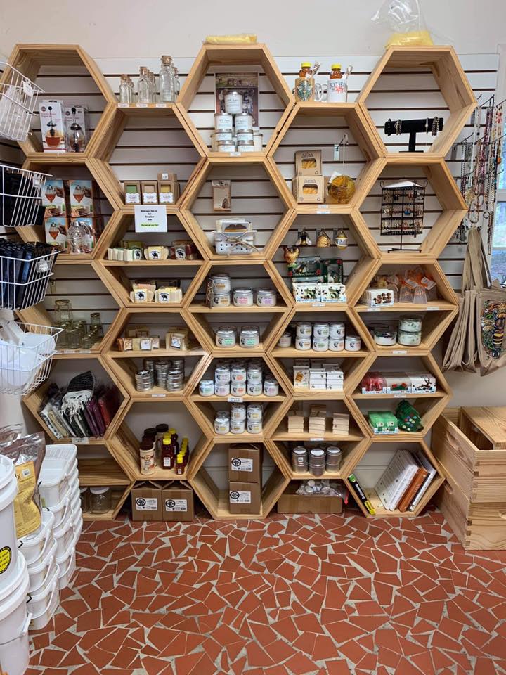 An assortment of body and skin care products in a wooden, honeycomb shelf structure at Blythewood Bee Company.