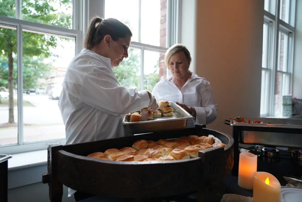 Two Cinnamon Hill Kitchen employees serving food at a catering event