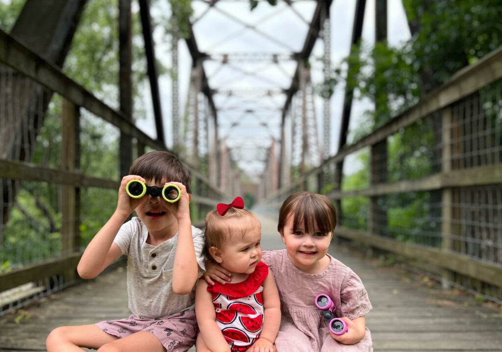 three children sitting at the base of the trestle trail.
