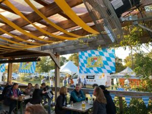 A view of WECO Bottle & Biergarten's outdoor patio during their annual Oktoberfest weekend celebration with Flags of Bavaria, food trucks, food vendors, and beer