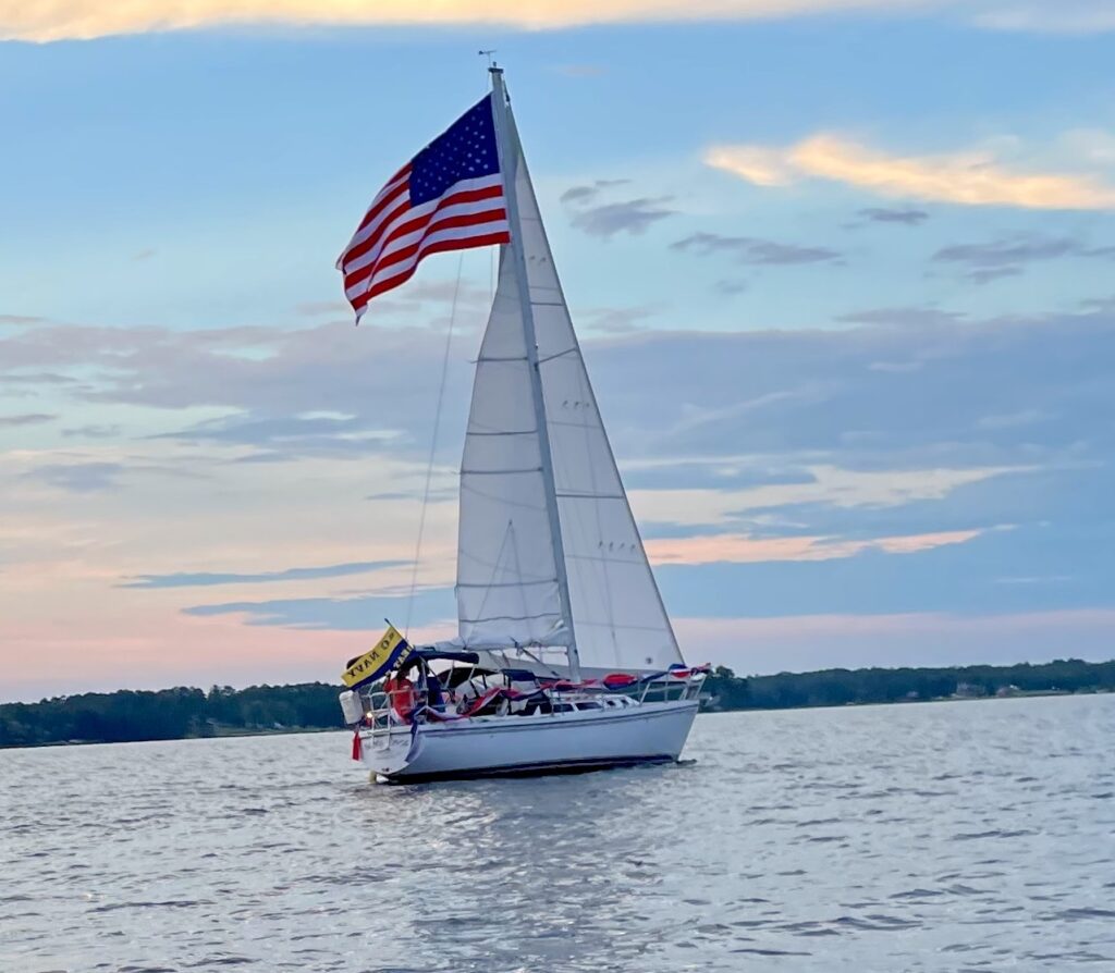 A sailboat with an American flag gracefully sails on the water, showcasing the beauty of Lake Murray and patriotism.